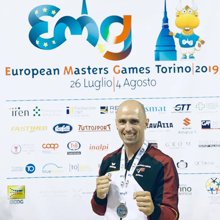 Thomas Lamm mit Medaille vor der Wand der European Masters Games Turin 2019
