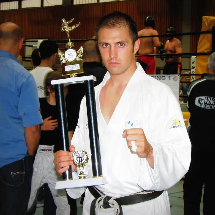 Thomas Lamm im Karateanzug mit einem großen Pokal